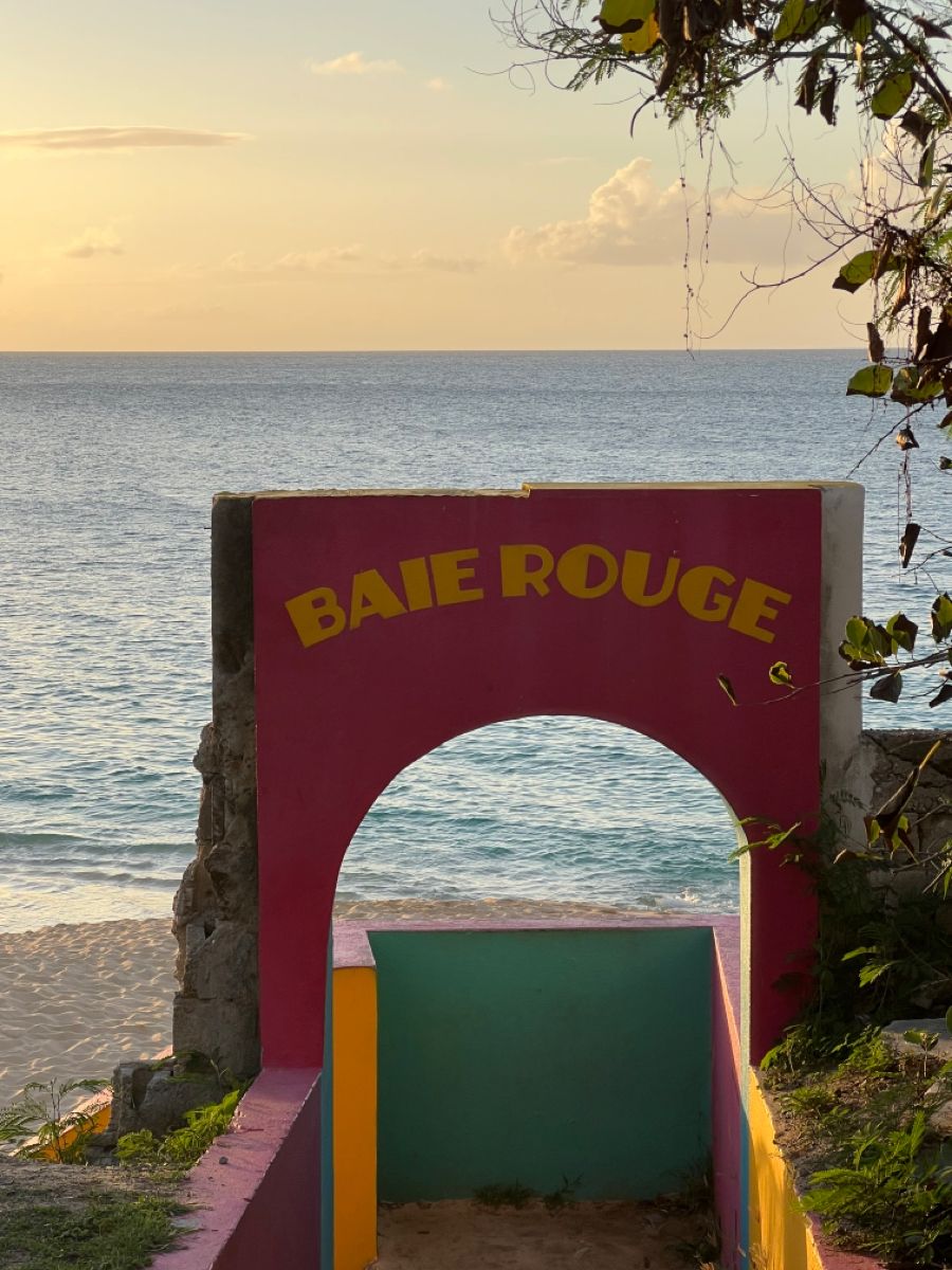 Colourful Baie Rouge beach entrance arch at sunset