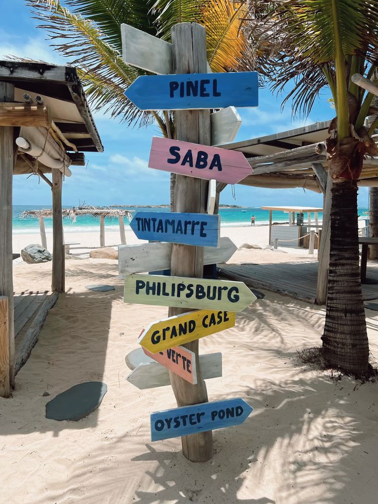 Wooden directional signpost on the beach pointing to Pinel, Saba and Philipsburg