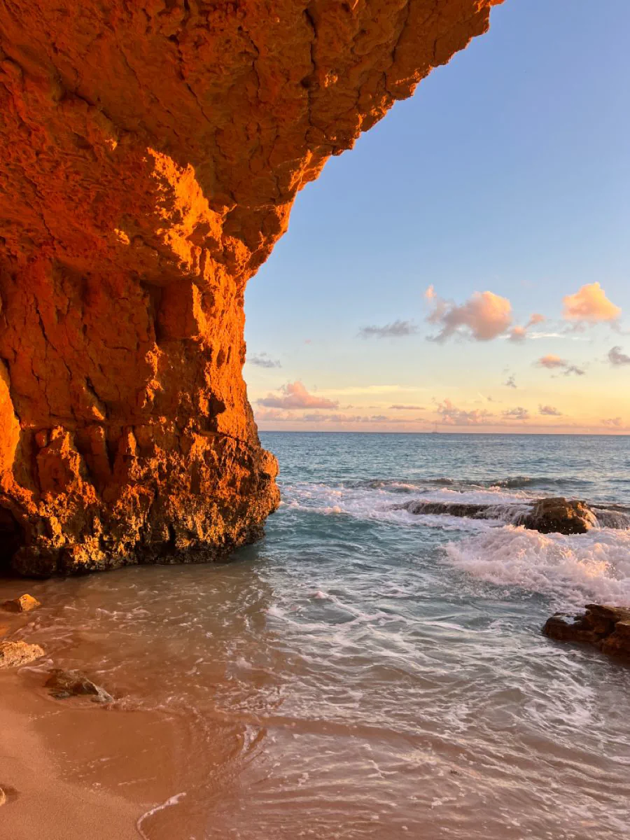 Sunlit rock overhang beside the surf on a Sint Maarten beach